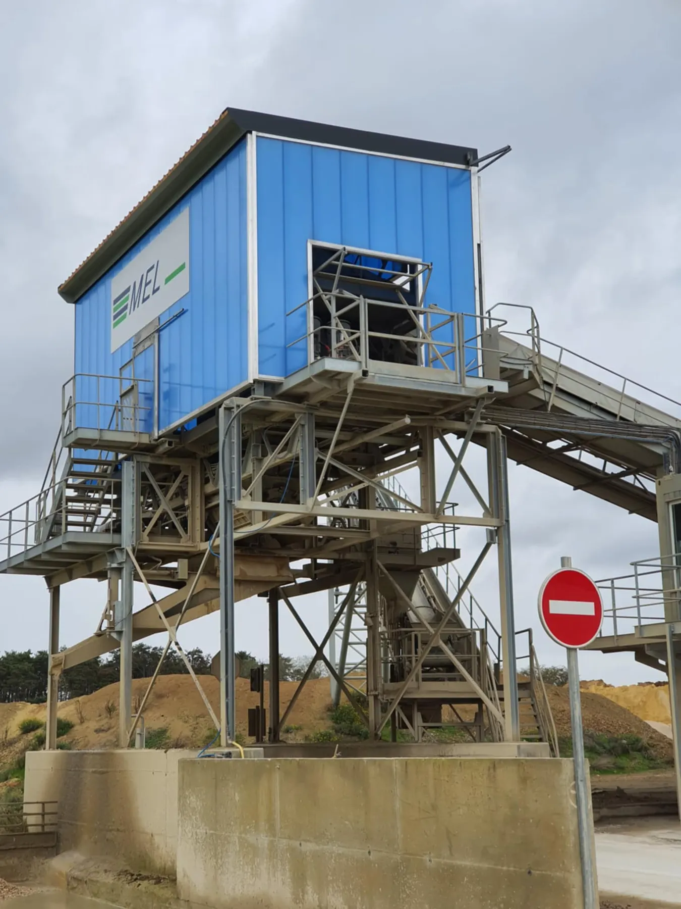 Tour de criblage surmontée d'une cabine habillée de bardage bleu portant le logo MEL