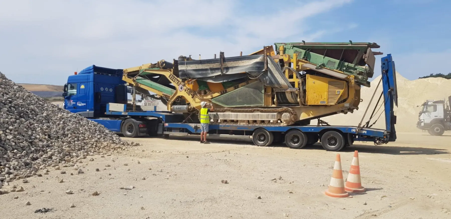Crible mobile sur chenilles chargé sur un porte-engin, dans une carrière